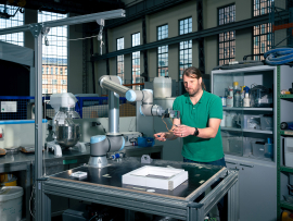 Mit diesem kleinen Roboterarm erforschen Timo Hartmann und sein Team, wie einglasige Fenster demontiert und zu mehrglasigen Fenstern wieder zusammengesetzt werden können. Der Roboterarm steht in der Peter-Behrens-Halle der TU Berlin. Foto: © Kevin Fuchs 