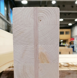 Stirnansicht eines Trägers aus holzbewehrtem Holz (HBH): In der Mitte des neuartigen Holzbauelements ist die integrierte Furnierbewehrung, die sogenannte Superlamelle, gut zu erkennen. Sie trägt zur Steigerung der Biege- und Zugfestigkeit bei. Bild: Niklas Kainz, TUM