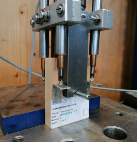 Wie ist die Druckfestigkeit entlang der Lochwand, welche Kräfte durch Verbindungsmittel wie Bolzen, Schraube oder Nagel können von der Superlamelle aufgenommen werden, ohne dass das Holz zerdrückt oder ausreißt? Die sogenannte Lochleibungsfestigkeit wird mit dieser Versuchsanordnung geprüft. Bild: Niklas Kainz, TUM